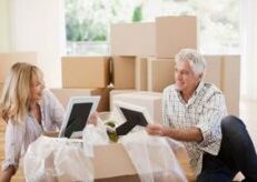 Middle-aged couple looking at iPads among moving boxes