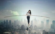 Photo of a woman on a high wire against the cityscape